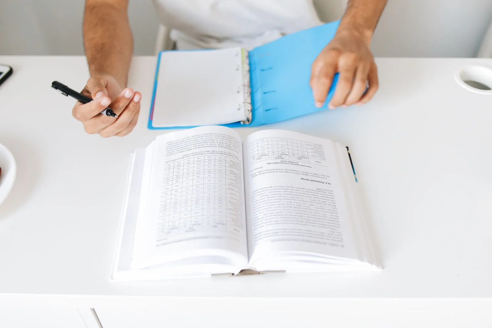 Close-up of a person taking notes from an open book and binder on desk. Which translation agencies deserve a shortlist
