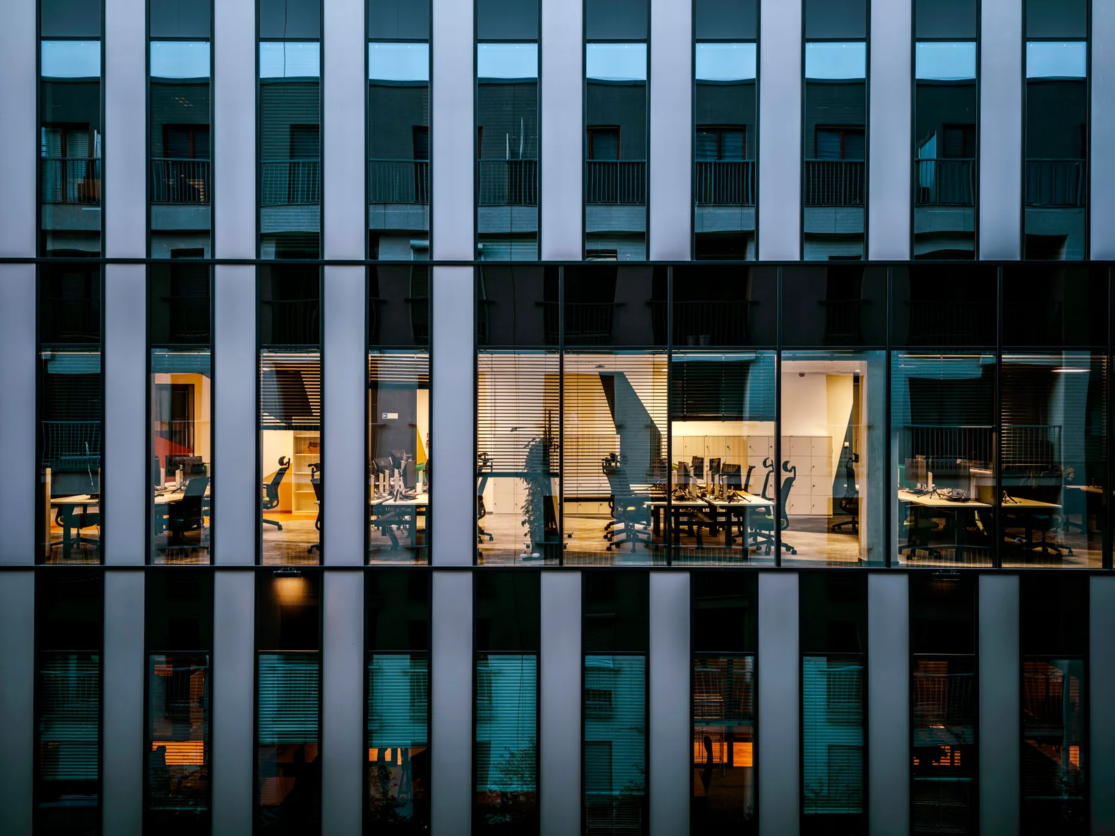 Illuminated office inside a modern glass building exterior, showcasing architecture and workspace design. Translation Agency Sales Tax by State: Texas, New York & Florida